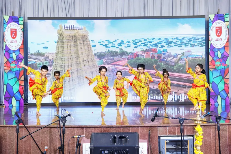 Children in yellow dance in front of a temple-tower backdrop