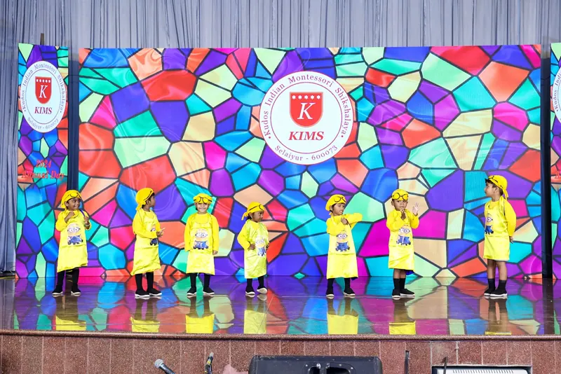 The youngest children in yellow perform before the stained-glass KIMS backdrop