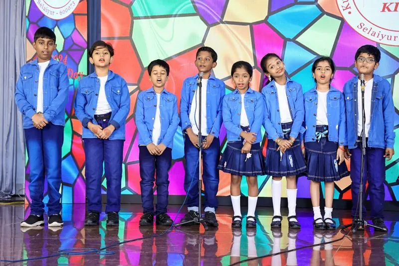 Children in blue blazers line up on stage