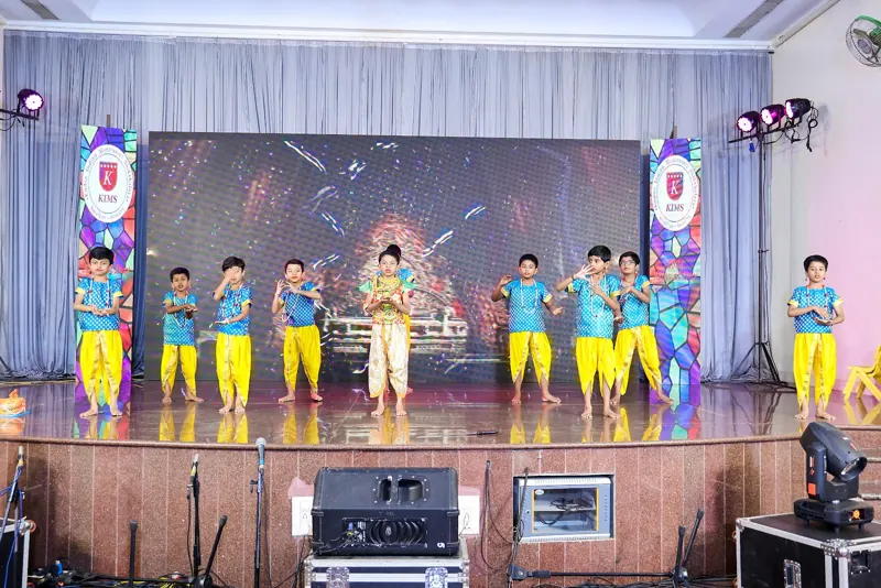 Children in blue and yellow perform a dance drama