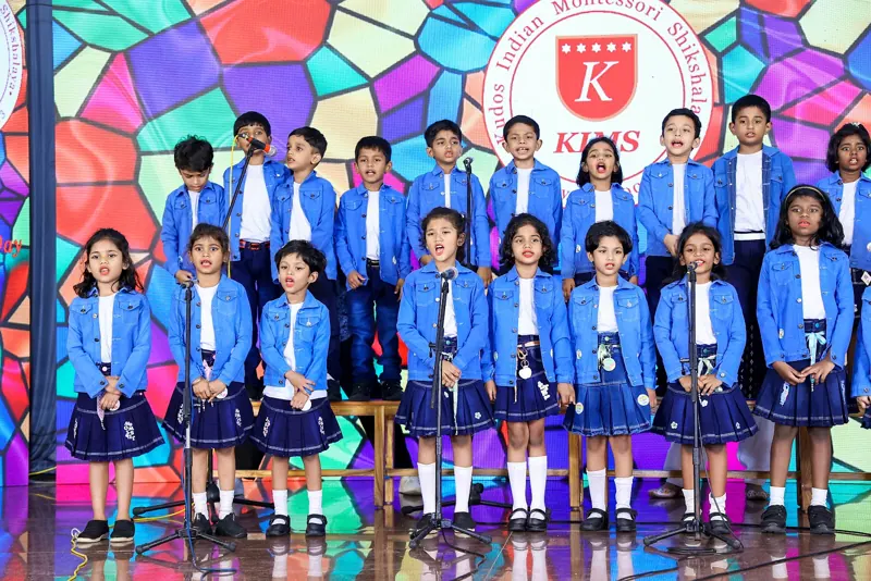 Children in blue blazers sing on stage