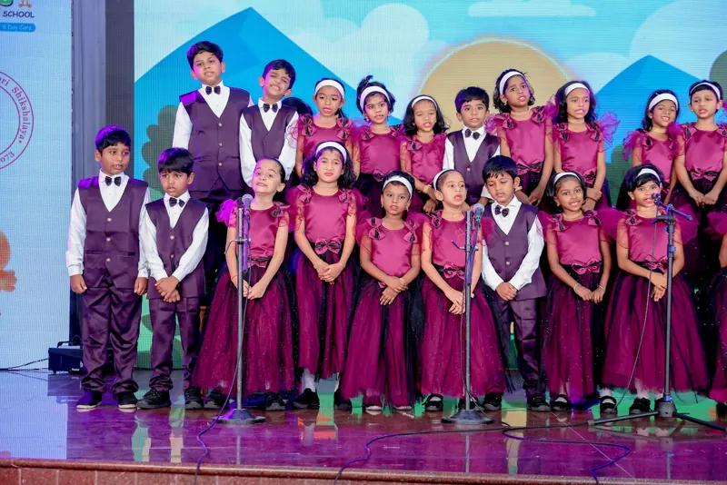 Children in maroon and purple sing as a choir