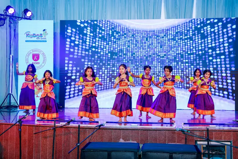 Girls in purple and gold perform a group dance