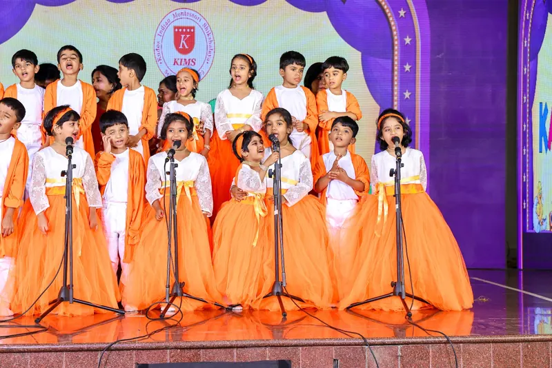 A choir in orange and white sings at the microphones