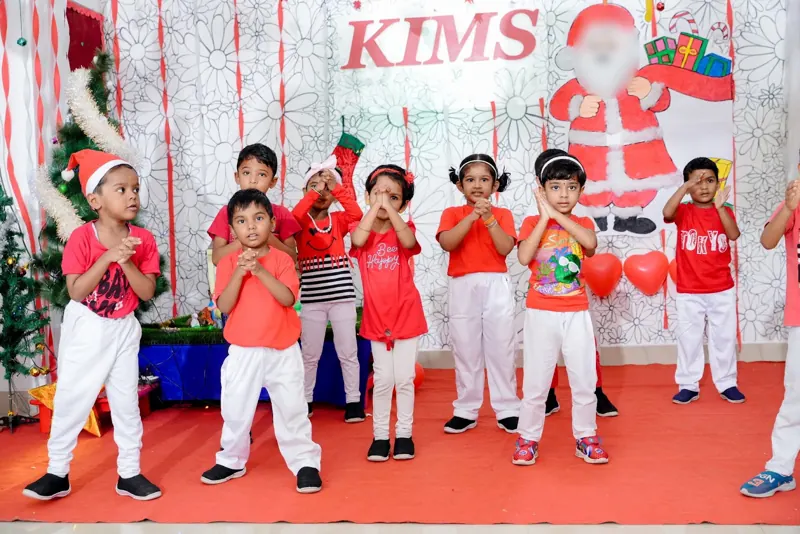 Children wave and dance under the KIMS sign