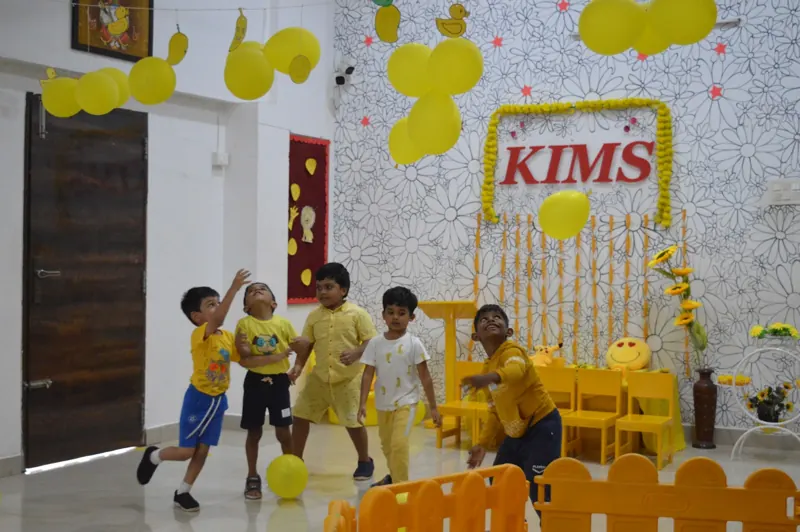Children toss balloons in the yellow room