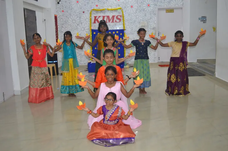 Girls in festive dress dance with diyas