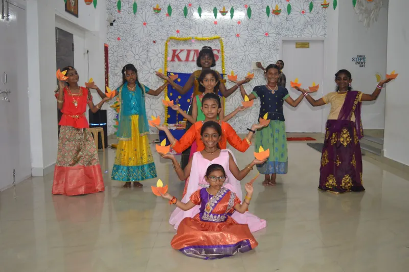 Girls hold up diyas in a dance formation