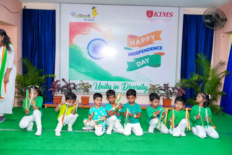 Children in green sit in a dance formation