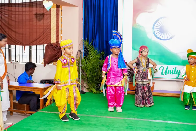 Children hold up paper flowers in the colours of the flag
