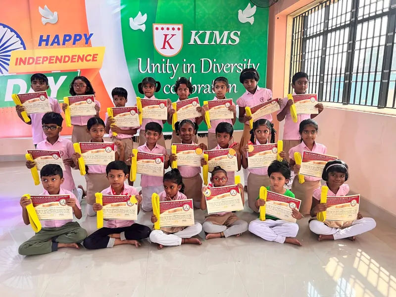 Children sit in rows holding certificates and belts