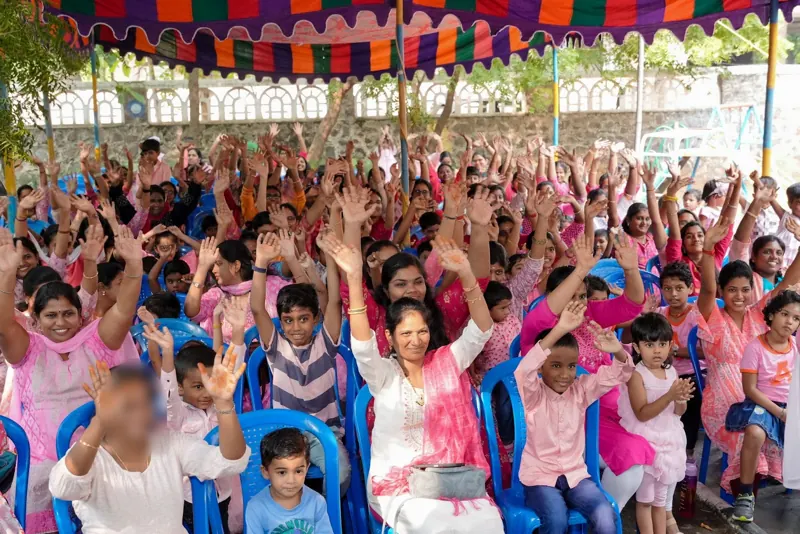 Mothers and children cheer with their hands up