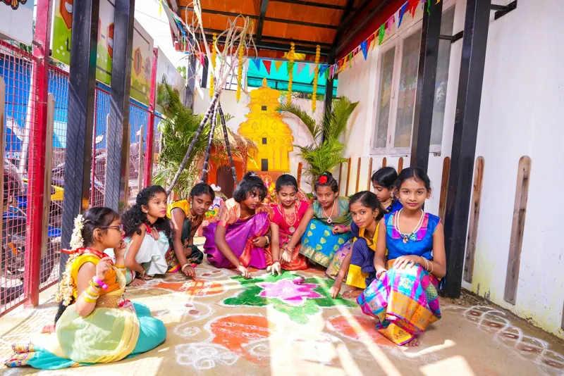 Girls in pavadai draw a kolam