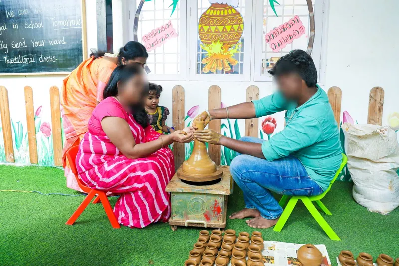 A potter shows children how to shape clay pots