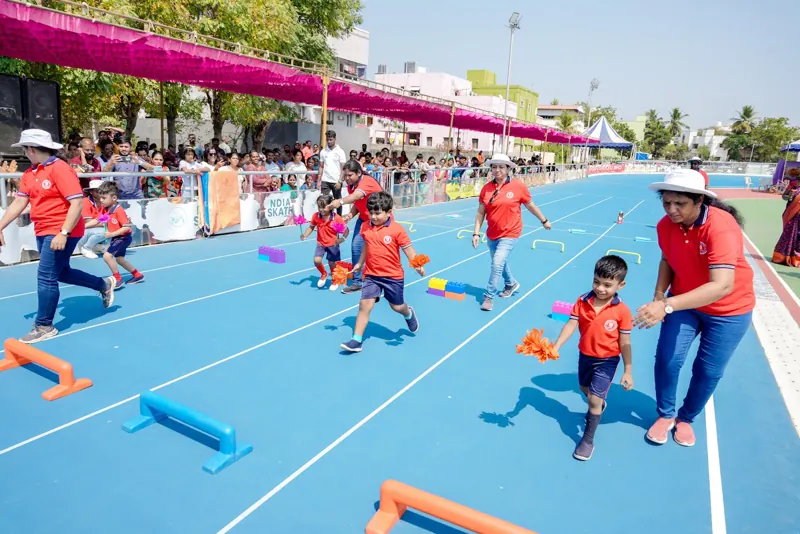 A teacher runs beside a child in a hurdle race