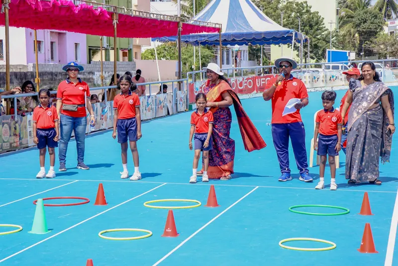 Children race between cones as teachers cheer