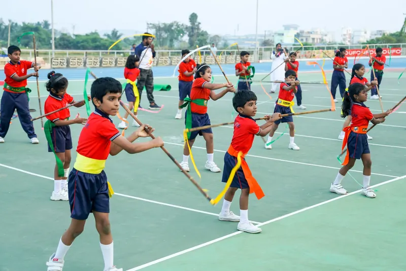 Older children perform a stick-and-ribbon drill