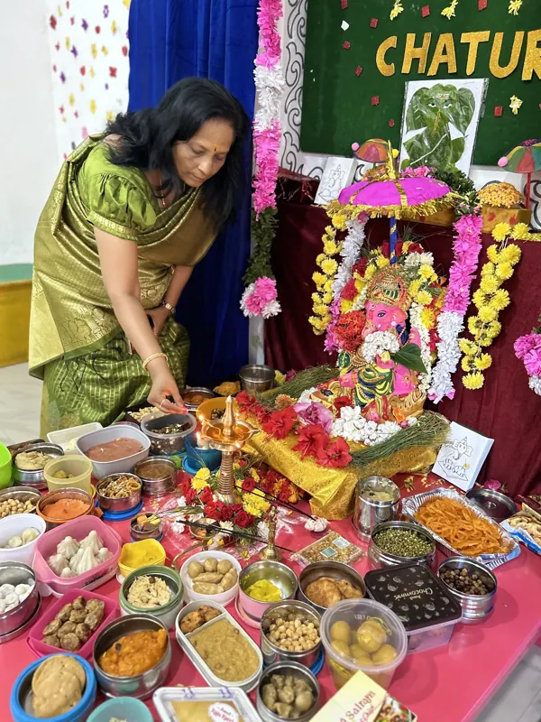 A teacher arranges the offerings at the Ganesha altar