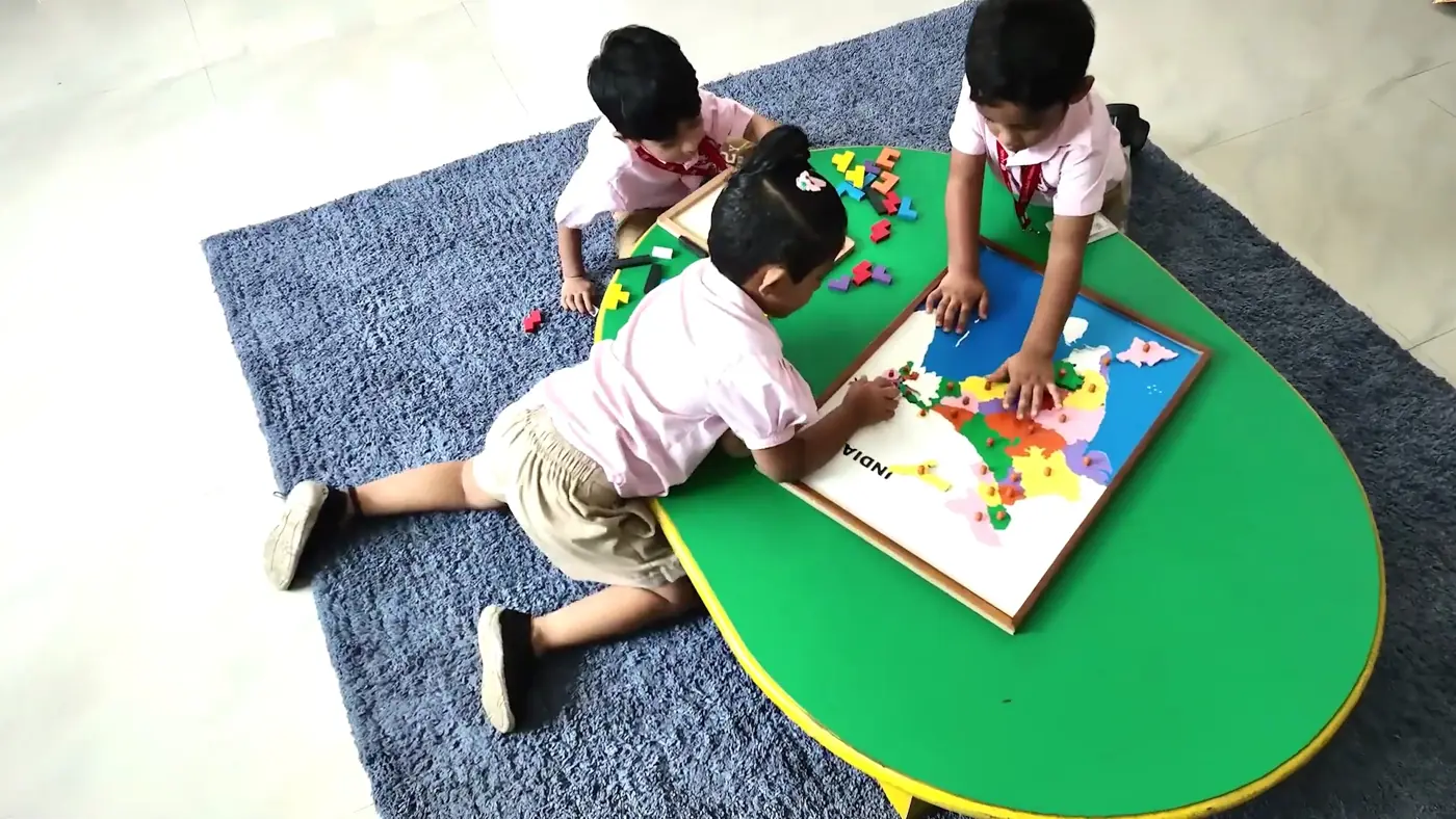KIMS children working on a Montessori map puzzle, seen from above